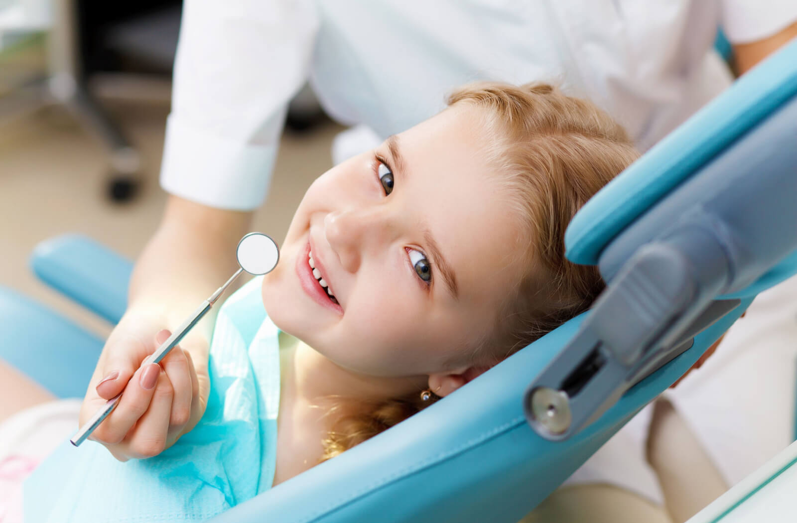 A dentist checking a child's teeth using a dental mirror