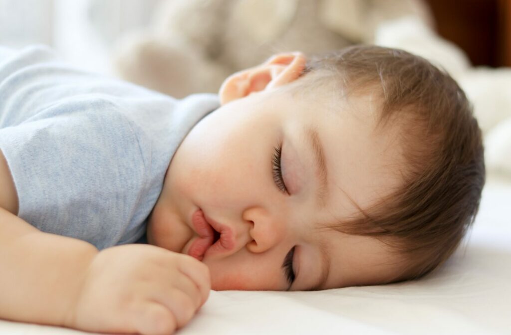 A baby sleeping soundly with their mouth open.